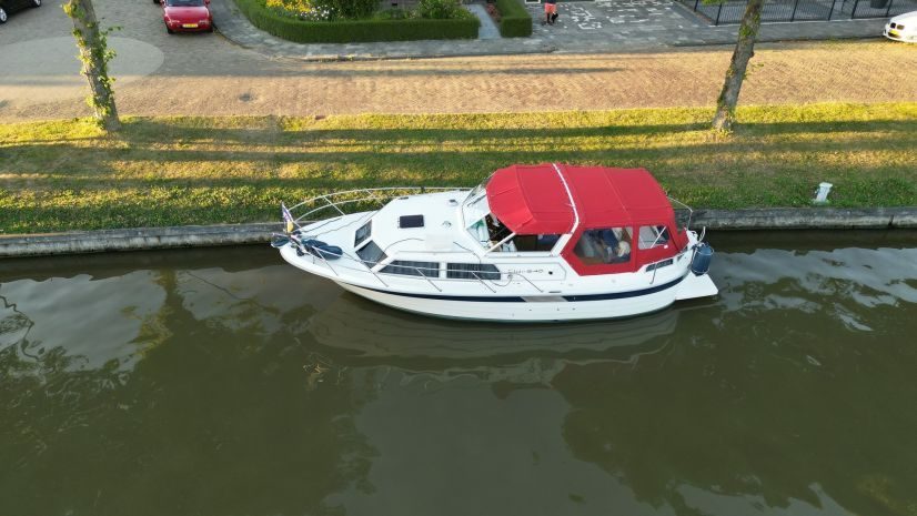 Bootverhuur Warten bovenaanzicht van witte boot met rode kap liggend aan de kade
